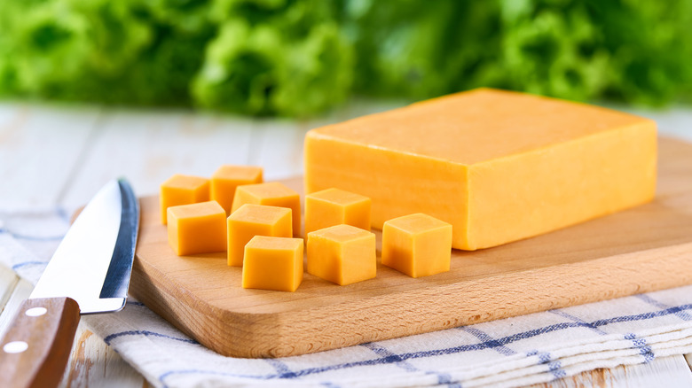 Cheddar cheese cubes on a wooden chopping board