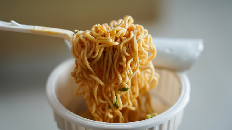 Close-up of instant ramen noodles being scooped from a cup