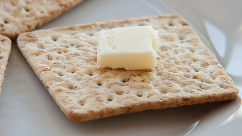 Close-up of a cracker with a pat of butter on top