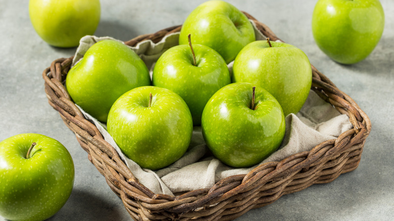 A basket of Granny Smith apples on a gray background