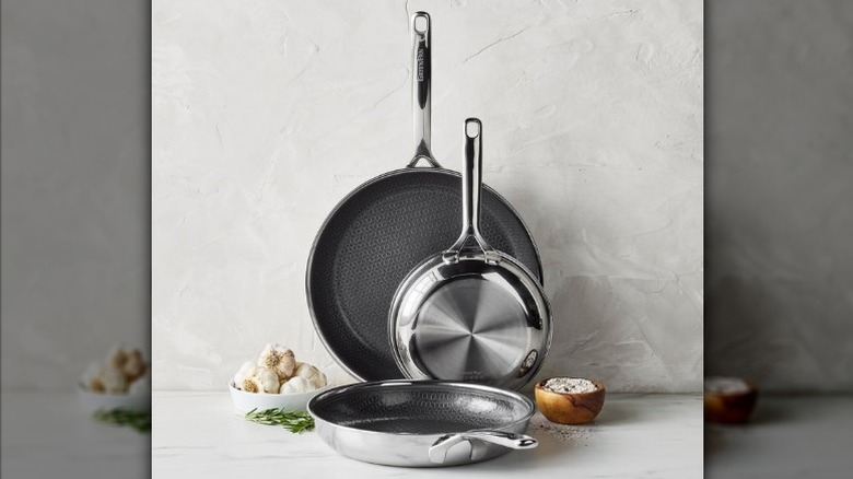 Set of three GreenPan Spectra Hybrid frying pans next to a bowl of garlic
