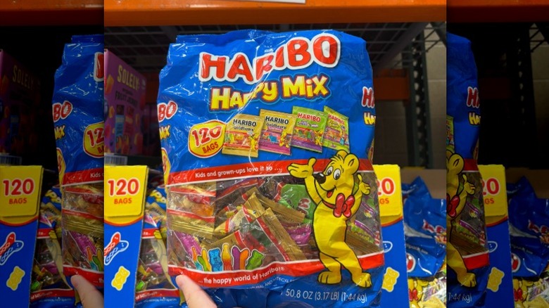A person holding a 120-count bag of mixed Haribo gummies