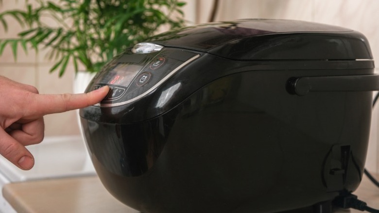A person pressing the button on a kitchen appliance