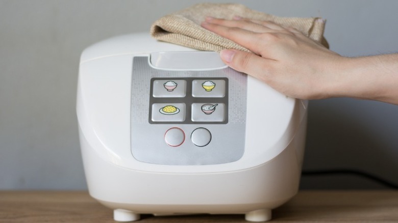 A person wiping down a rice cooker