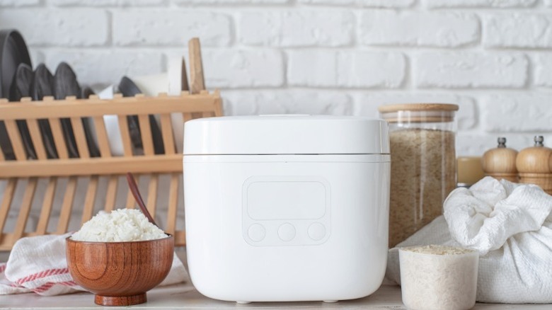 A rice cooker sitting amongst other things on a kitchen counter