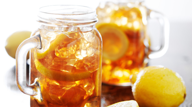 Closeup of jars of sweet tea and lemon on a table.