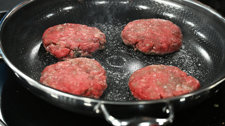 Hamburgers cooking in a HexClad non-stick skillet