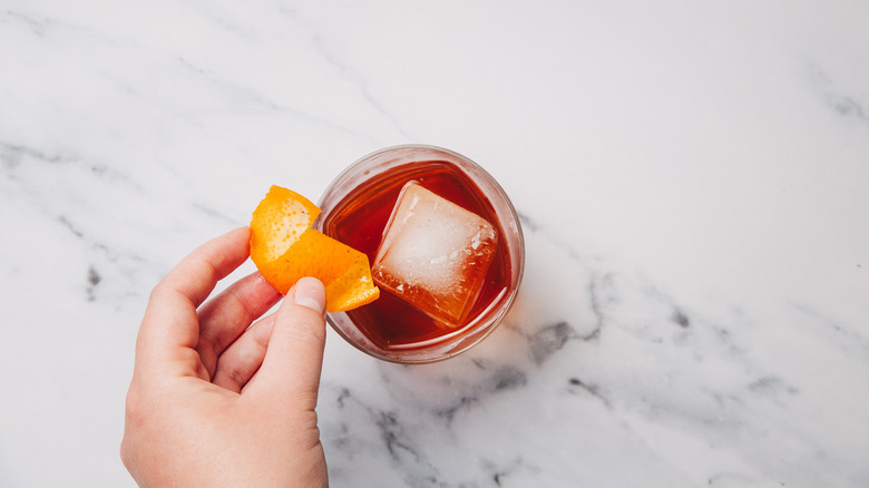 Expressing orange peel over drink