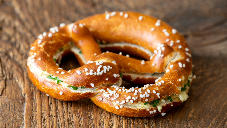 A Bavarian pretzel cut in half with butter and chives in the middle.