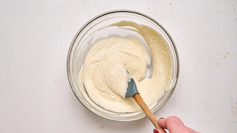 stirring cream sauce together in a bowl