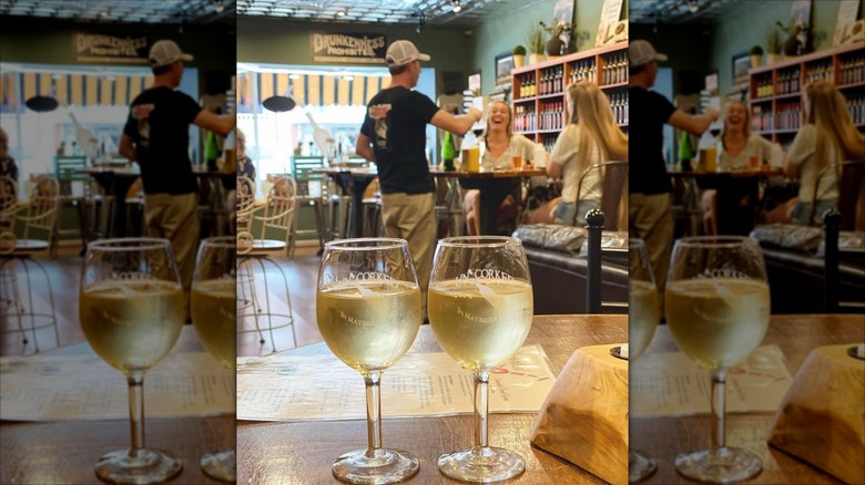 Two glasses of wine on a table with people laughing in the background