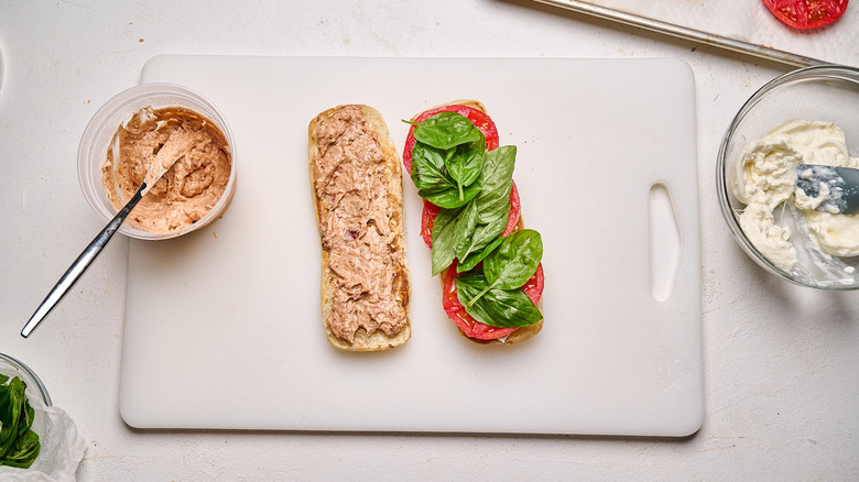 Open faced tomato sandwich with aioli on one side and tomatoes and basil on the other