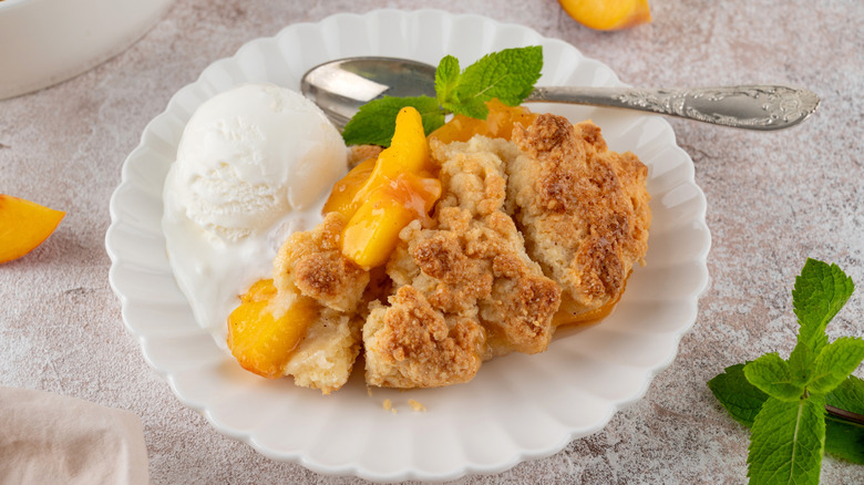 Peach dump cake and ice cream on plate with spoon