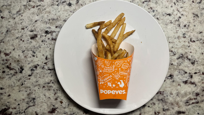 Popeye's cajun fries in a container and on a plate
