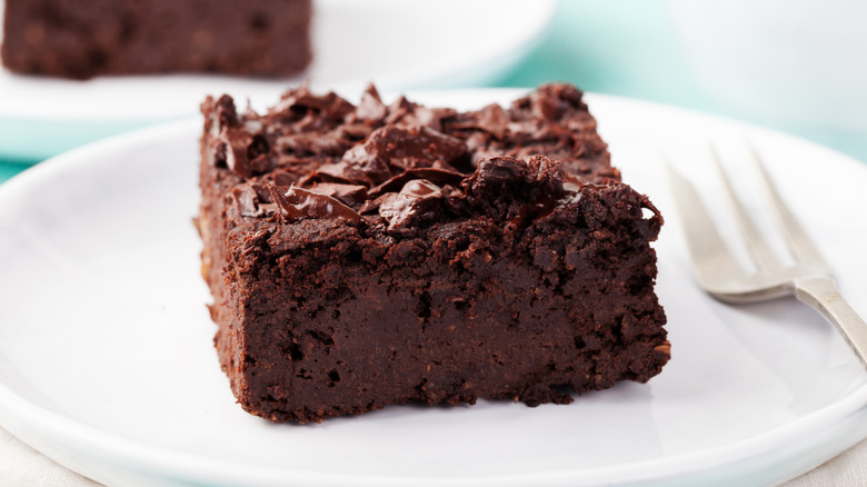 A fudgy chocolate brownie on a plate with a fork