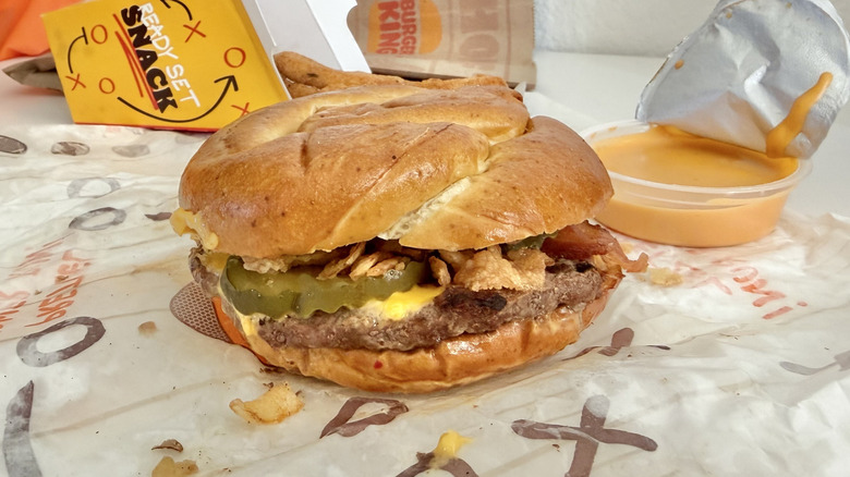 Game Day Pretzel Burger on a paper wrapper with cheese sauce in background