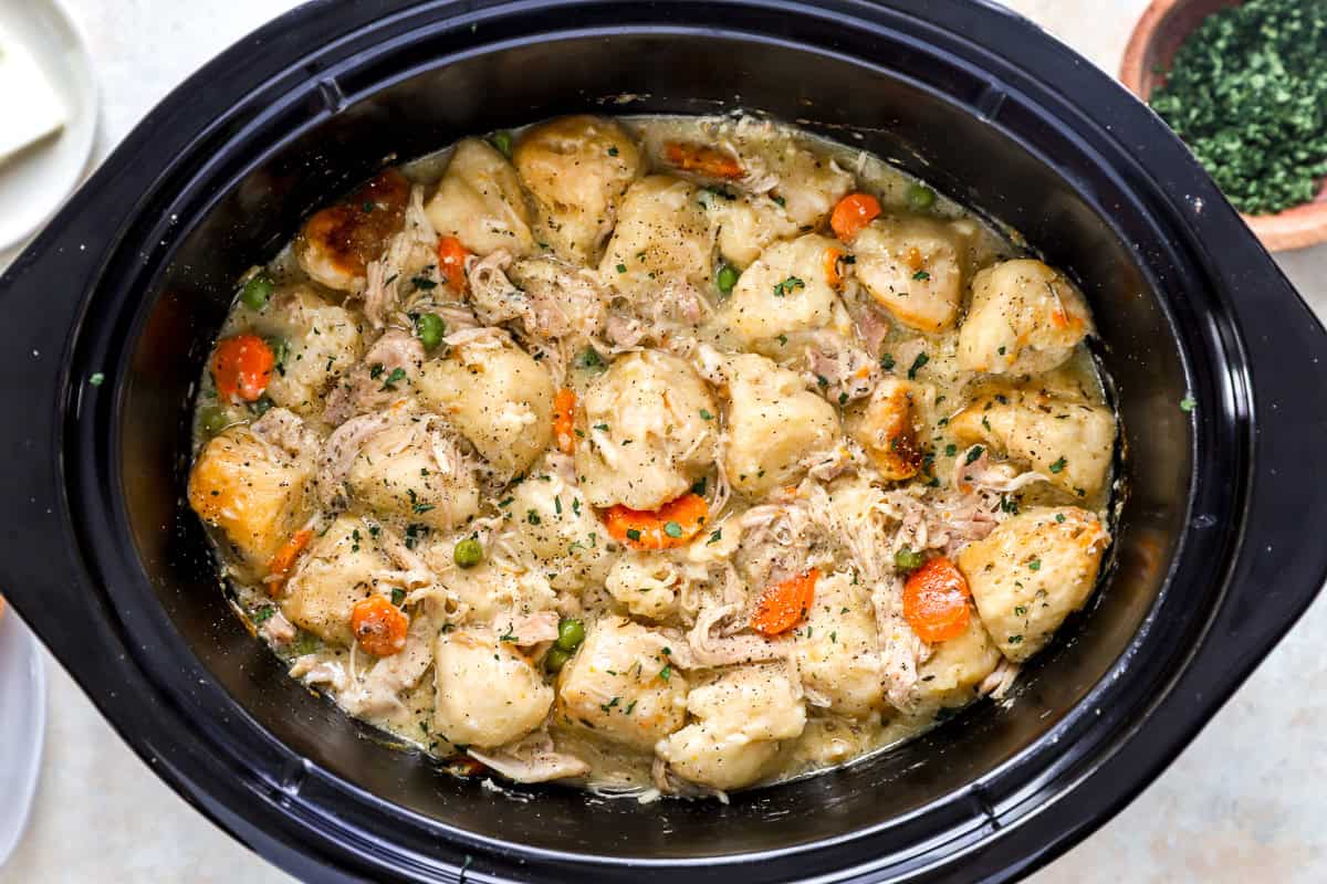 Fully cooked biscuit dumplings with matte tops and golden brown edges filling the top of a slow cooker.