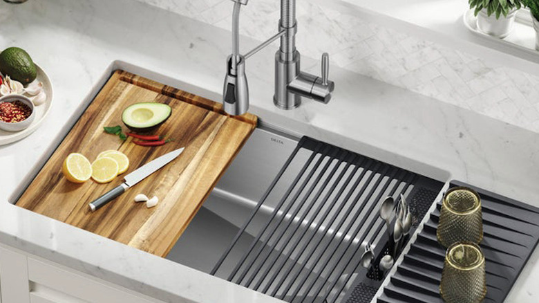 A kitchen sink with cutting board and dish rack
