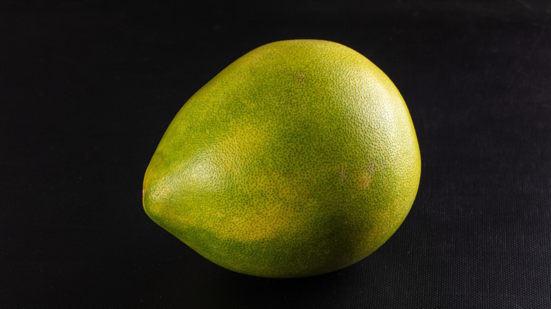 A whole, yellow-green oroblanco on black background