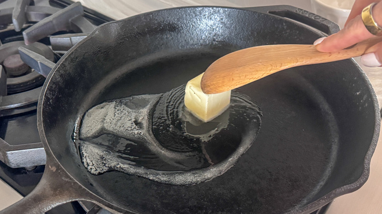 hand stirring butter in skillet