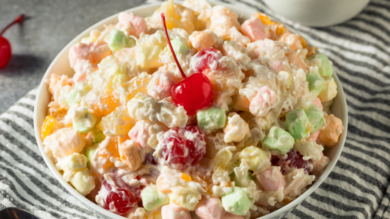 A colorful ambrosia salad topped with a cherry