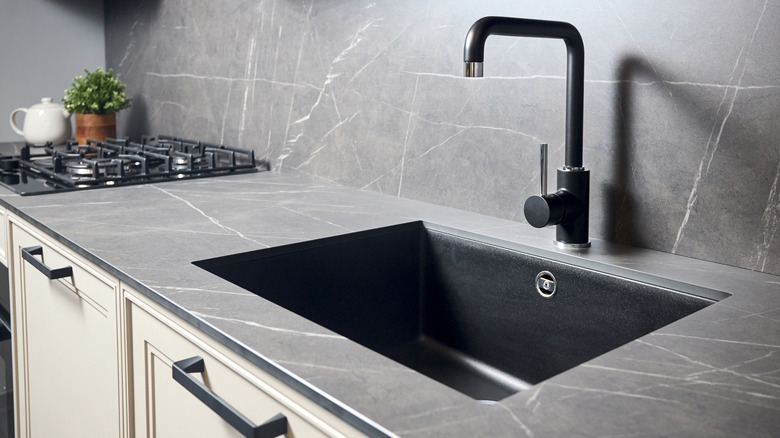 A black matte countertop surrounding a black kitchen sink