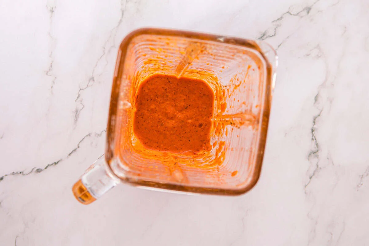 Overhead view of smooth red-orange peri peri marinade in a blender.