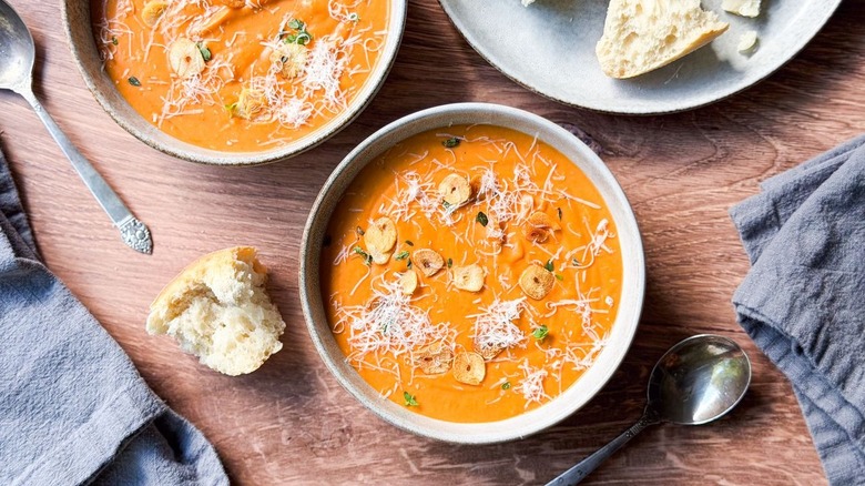 Ultra-creamy white bean tomato soup in serving bowls with spoons and bread