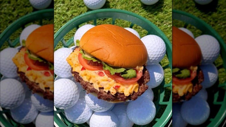 Shake Shack Clubhouse Pimento Cheese Burger sitting on top of golf balls inside green basket