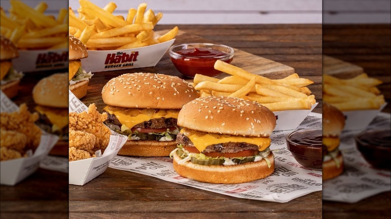 Habit Burger Char Sliders mini burgers next to french fries, fried chicken, and cups of dipping sauce.