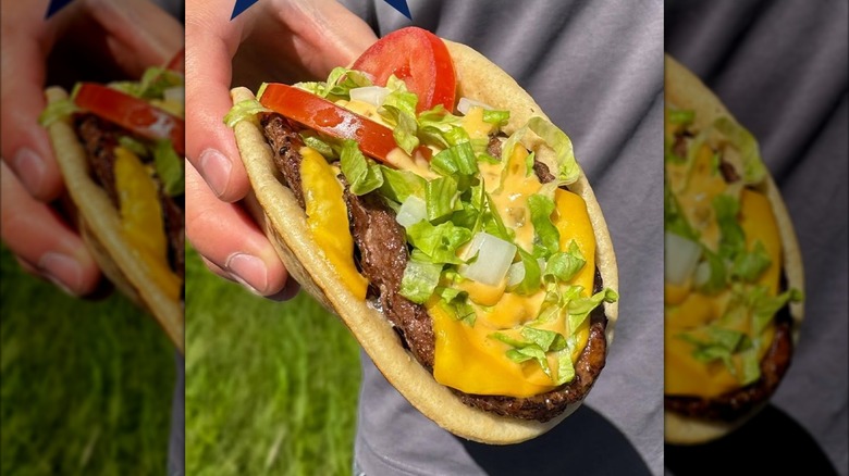 Hand holding Del Taco All-American Burgertaco