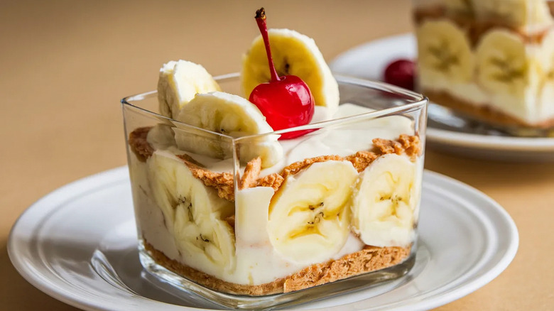 A square glass bowl holds a creamy banana pudding with granola crumble
