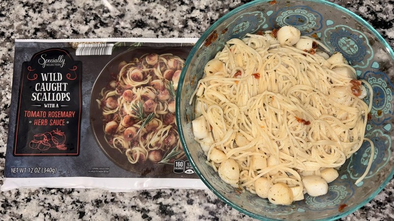An empty bag of Specially Selected Wild-Caught Scallops next to a bowl of pasta topped with the scallops and sauce