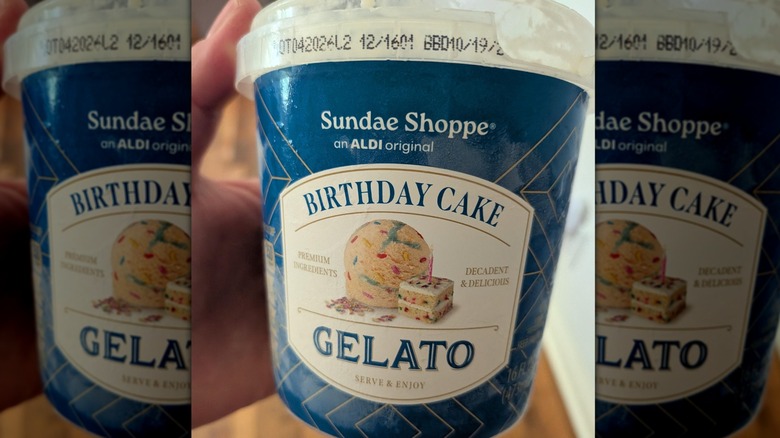 A close-up photo of a person holding a pint of Sundae Shoppe Birthday Cake Gelato from Aldi