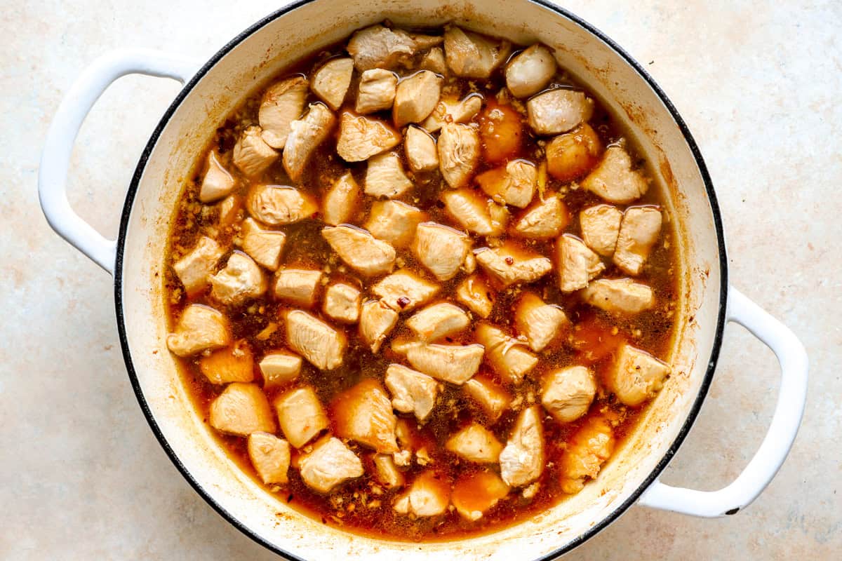 Browned chicken pieces added to the thin bourbon sauce in a skillet, ready to simmer.