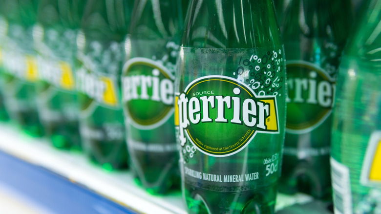 Bottles of Perrier line a grocery store shelf.
