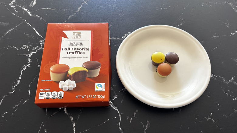 A Moser-Roth Fall Favorite Truffles box next to three truffles, each a different color, on a white plate