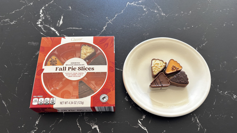 A Choceur Fall Pie Slices chocolate box next to pie-shaped chocolates on a white plate