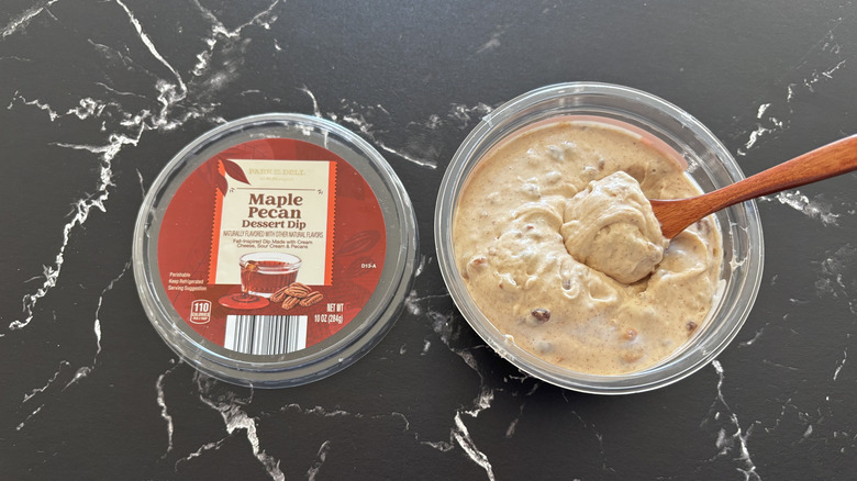 A tub of Parker Dell Maple Pecan Dessert Dip with its lid removed and a wooden spoon in the dip