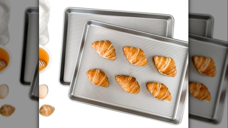 A half sheet pan with croissants next to a bowl of honey