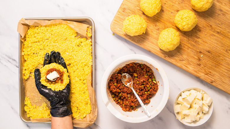 Hand holding stuffed but not rolled arancini