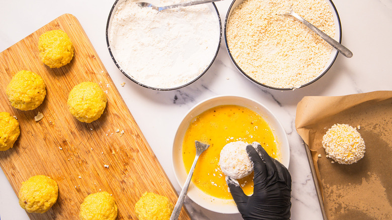Dipping rolled and coated arancini into egg