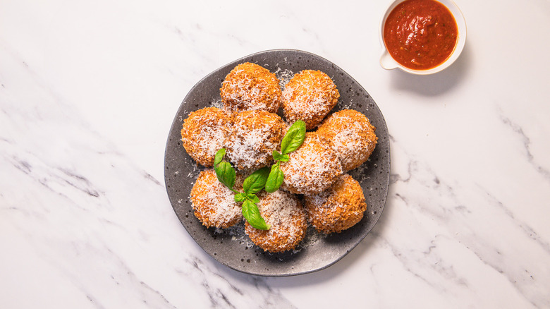 Arancini on a plate with marinara in small bowl