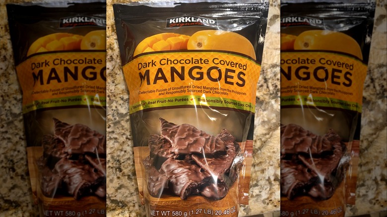 Bag of Costco Kirkland Signature Dark Chocolate Covered Mangoes on marbled surface.