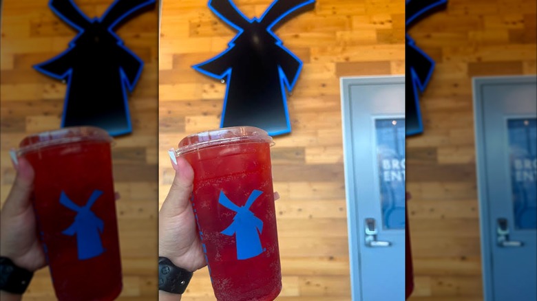 A hand holds a cup of Unicorn Blood aloft in a Dutch Bros.
