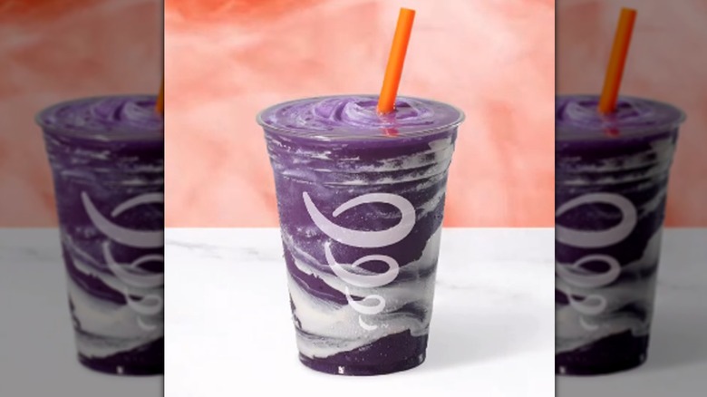 A cup of Berry BOO-st sits on a white marble counter in front of a pink smoky backdrop.