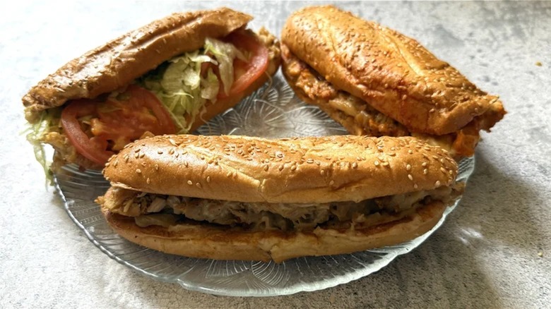 Arby's classic, deluxe and spicy Chicken Cheesesteaks arranged on a glass plate.