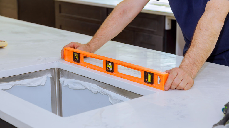 A man checks a newly installed countertop with a level