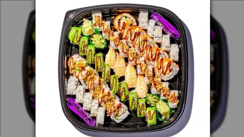 FujiSan Big Maki Combo Platter with an assortment of sushi, soy sauce packets, wasabi, and pickled ginger on a white background