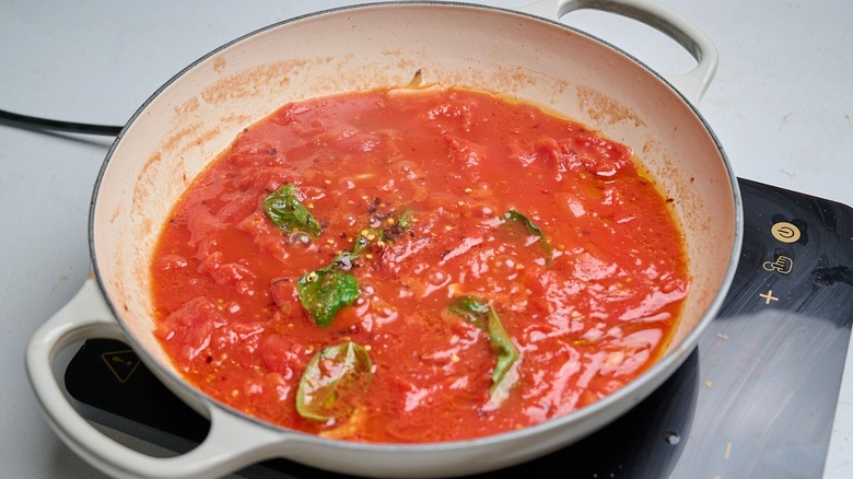 simmering tomatoes and basil in a skillet